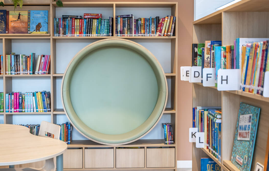 boekenkast met ronde zitnis en opbergbakken onderin op maat voor onderwijsinstelling